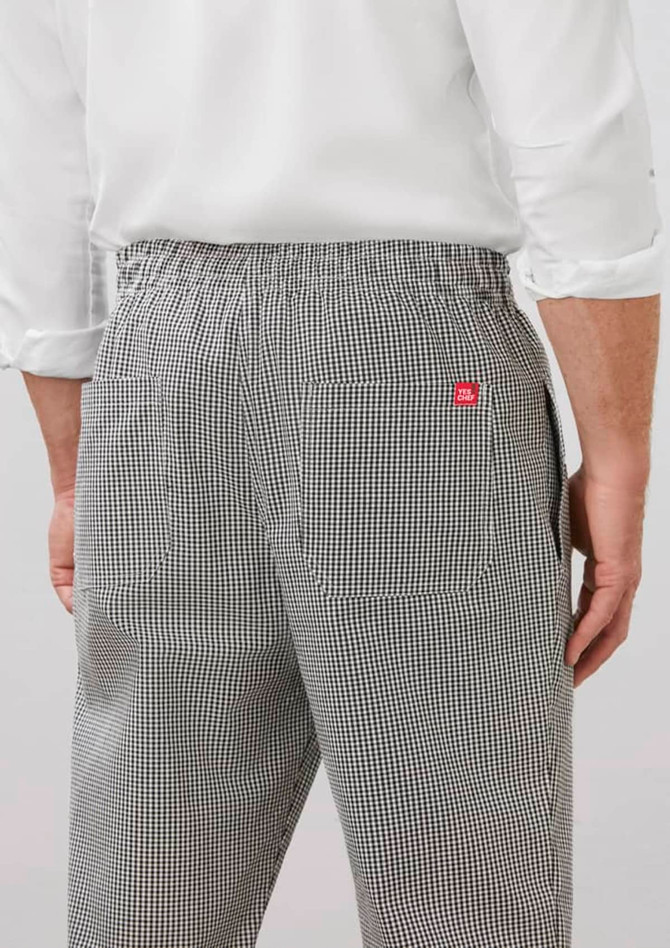 A pair of mens track pants in a black and white checkered pattern, featuring a waistband and pockets on the back.
