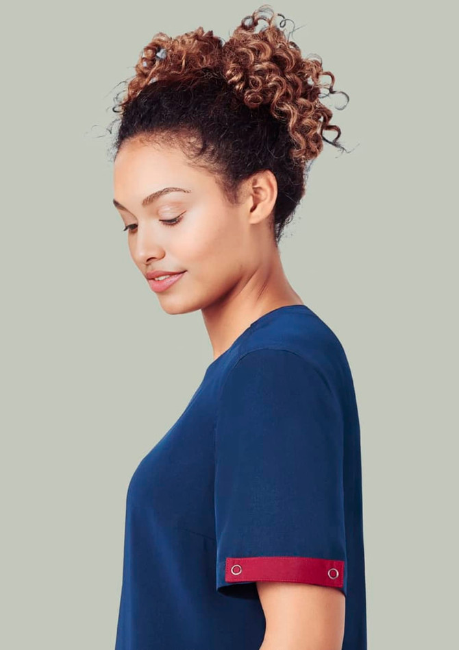 A navy scrub top with a burgundy accent on the sleeve, worn by a woman with curly hair.