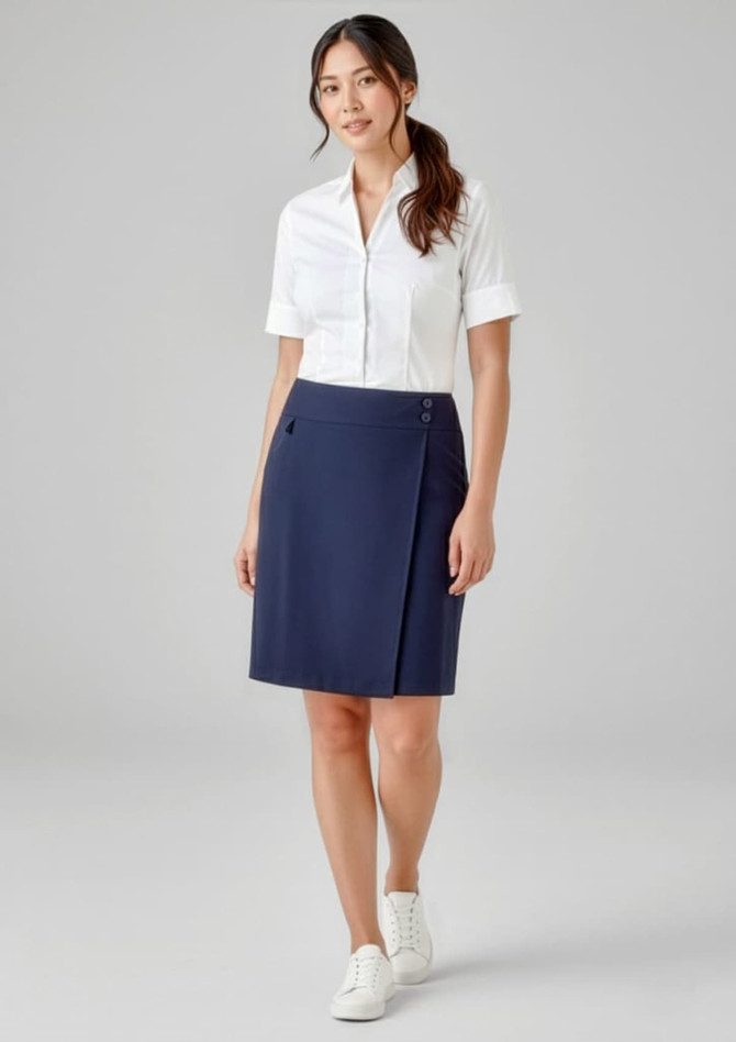 A woman wearing a navy skort and a white shirt, standing in a neutral background. The skort features a logo.