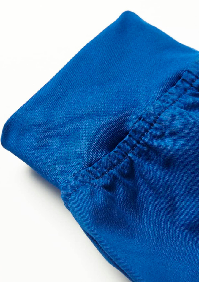 A close-up of blue women's jogger scrub pants featuring elasticised cuffs and a smooth fabric finish.