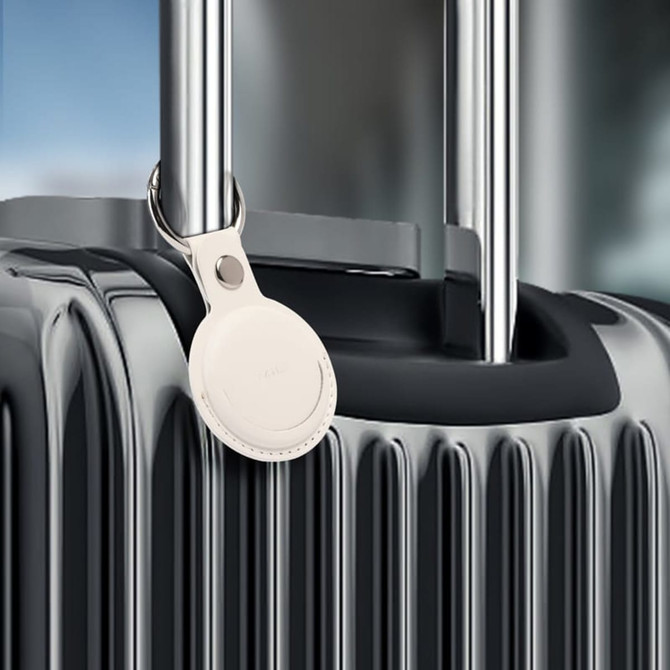 A sleek silver tracking tag attached to a black suitcase handle, featuring a simple logo.