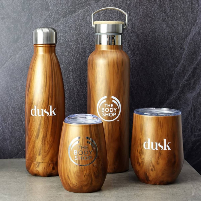 A drink bottle and assorted drinkware in a wood-like finish, featuring silver accents and branding logos.