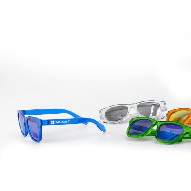 A pair of blue sunglasses alongside green, orange, and clear sunglasses, featuring a logo on the blue pair.