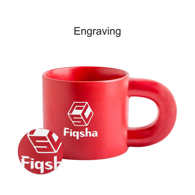 A red ceramic coffee mug with a large handle and an engraved logo.