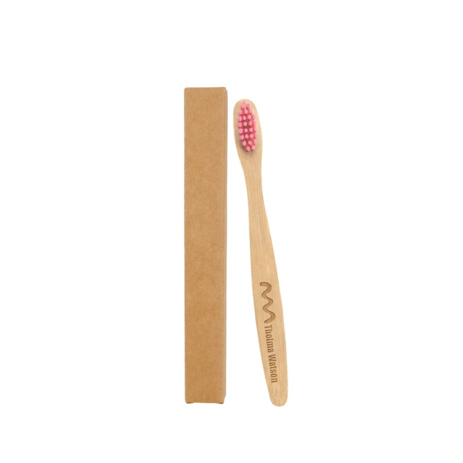 A small bamboo toothbrush with a pink bristle head, positioned next to its brown cardboard packaging.