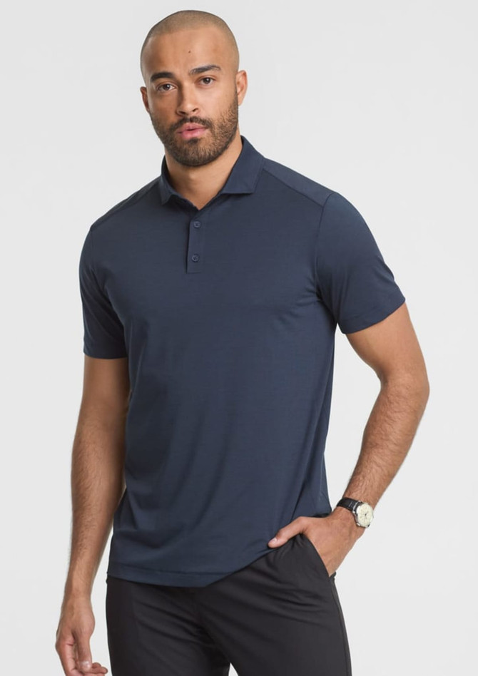A short sleeve polo shirt in navy blue, featuring a collar and a logo on the chest, worn by a male model.