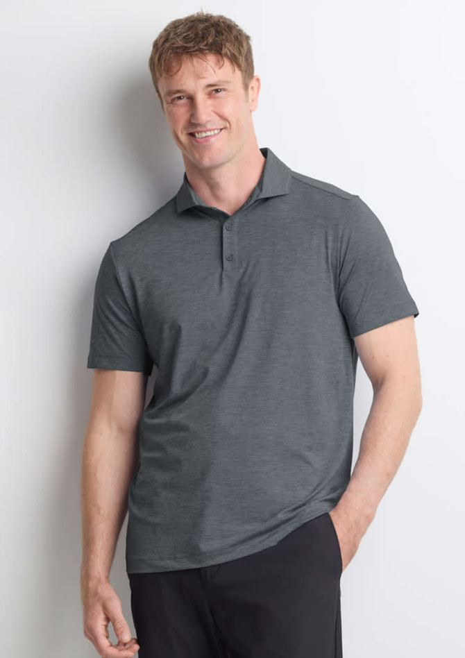 A man wearing a grey short sleeve polo shirt, standing casually with a friendly expression. The shirt has a collar and branding.