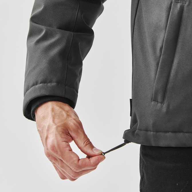 A hand adjusting the hem of a men's thermal jacket in a dark colour, featuring a logo on its side.