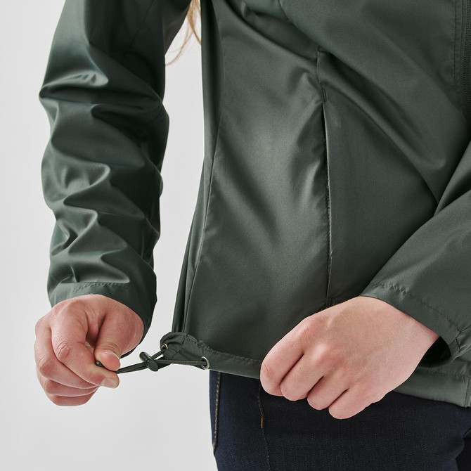 A green women's full zip rain jacket with a drawstring at the hem being adjusted by a person.