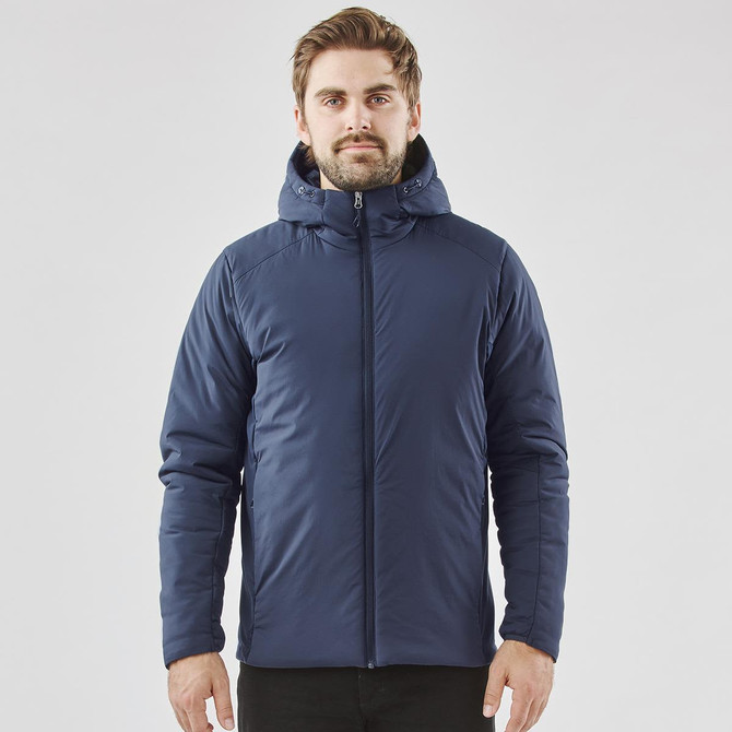 A man wearing a navy blue puffer jacket with a hood, featuring a logo. The jacket has a zip closure and a fitted design.