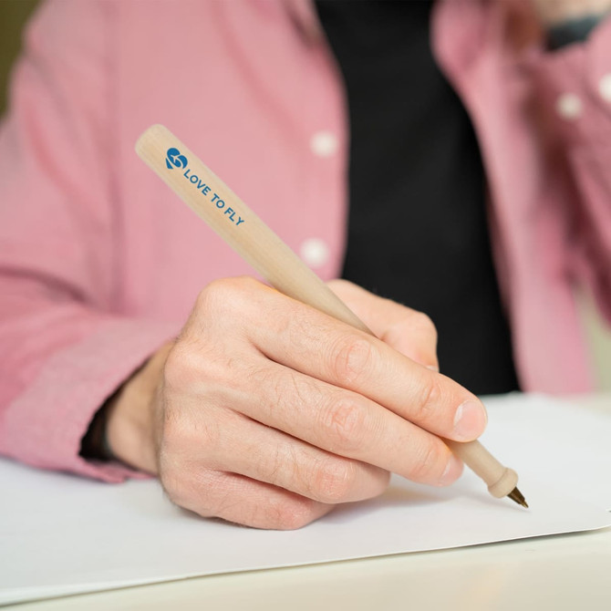 A wooden pen shaped like a baseball bat, featuring a logo, being held by a person.