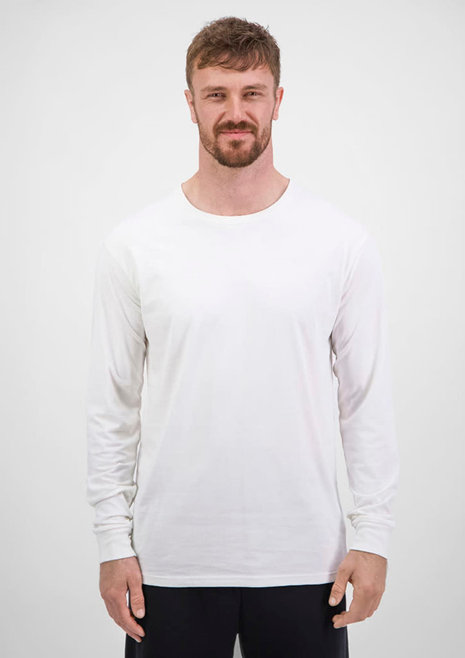 A man wearing a plain white long sleeve tee stands against a neutral background. The tee has a brand logo.