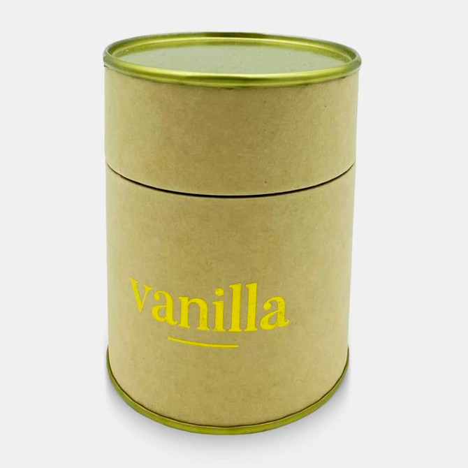A medium cylindrical candle in a natural cardboard container with a green lid, labelled 'vanilla' in yellow lettering.