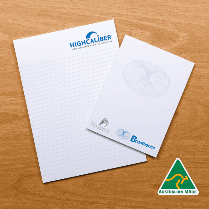 A4 notepad with lined pages, featuring a logo and an Australian Made badge, set on a wooden surface.