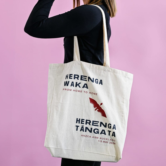 A calico tote bag with gusset, featuring a logo and text, displayed against a pink background.