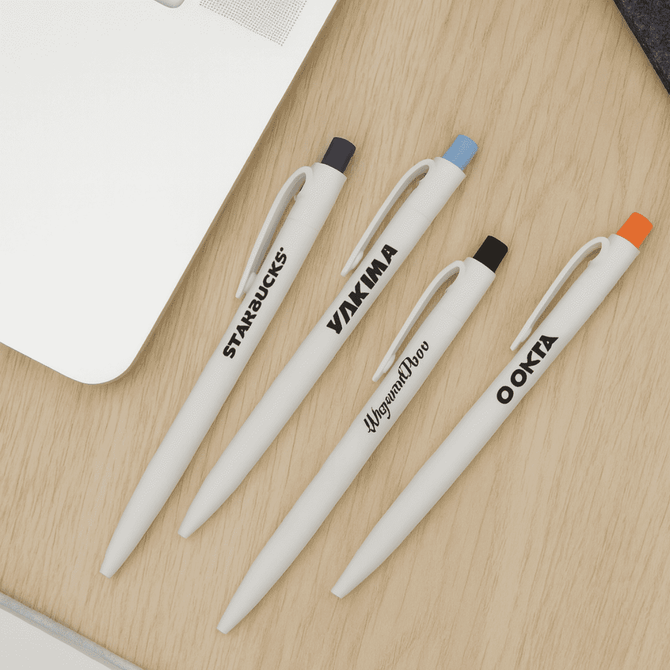 A collection of white plastic pens in black, orange, and blue with various logos on a wooden surface.