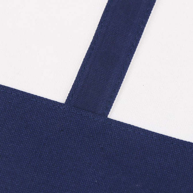 A small canvas tote bag featuring a navy blue bottom and straps, with a cream-coloured body and logo.
