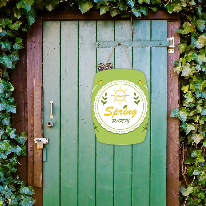 A green wooden signboard with "Spring Party" design, hanging on a wooden door surrounded by ivy.