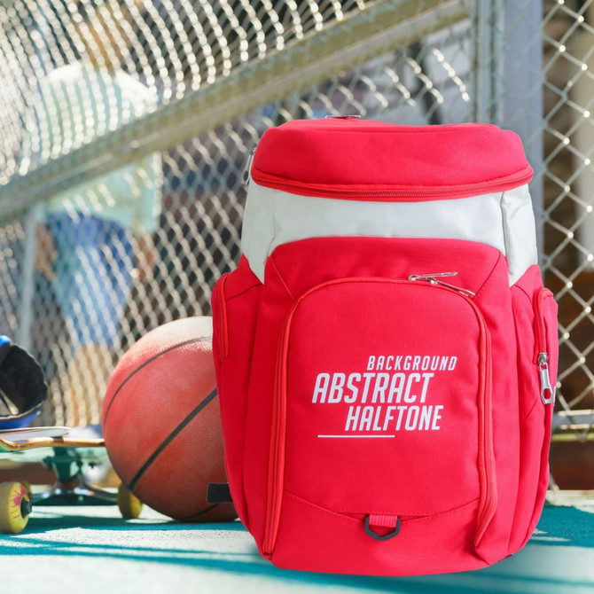A red basketball backpack is positioned near a basketball, with a skateboard visible in the background. The backpack features a logo.