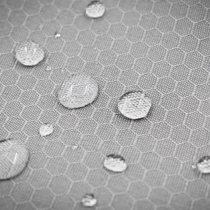 A close-up of a textured grey fabric with water droplets collecting on its honeycomb pattern, featuring a logo.