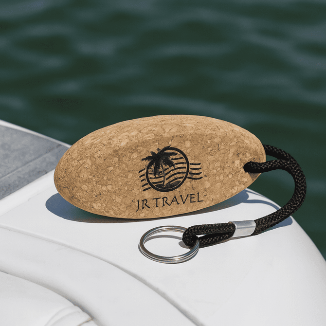 A cork keychain in an oval shape with a black rope and a keyring, featuring a logo with a palm tree.