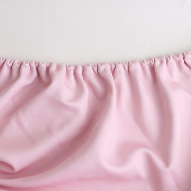 A pink table topper with gathered edges, featuring a smooth fabric texture. It has a branding logo present.