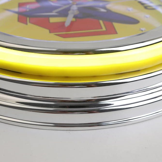 A wall clock featuring a yellow neon ring and shiny chrome details, with a colourful design in the centre.