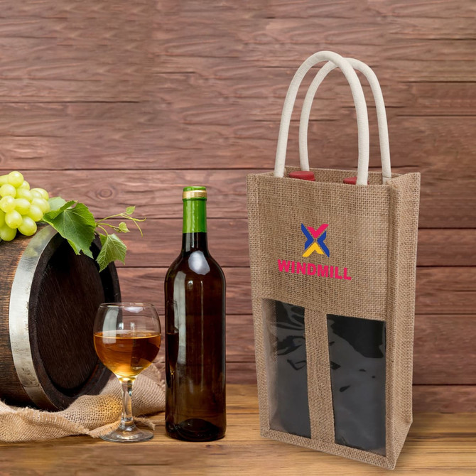 A jute double wine carrier in brown with a window, featuring two compartments and white handles. A wine bottle and glass are alongside.
