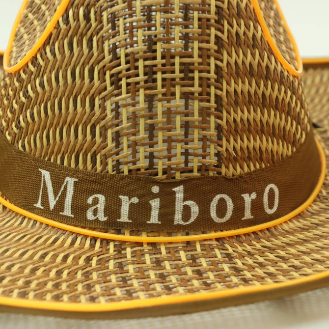 A light brown straw hat with orange accents and a fabric band featuring a logo.