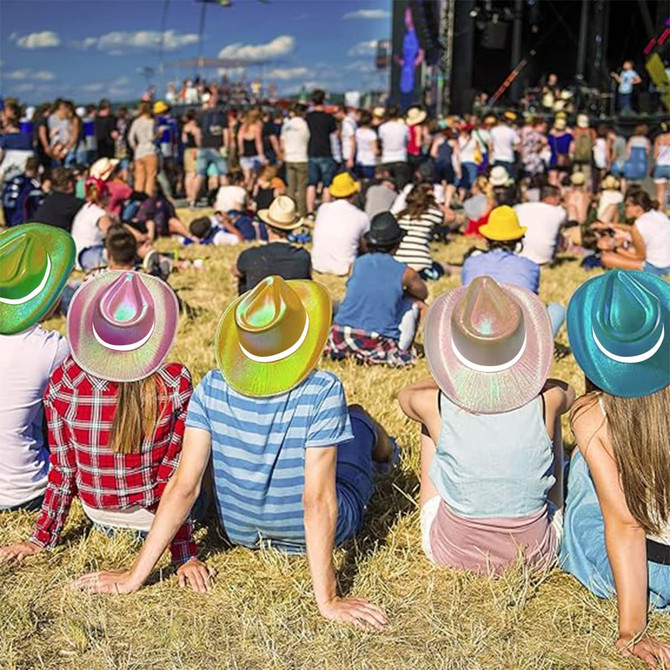 A group of people sitting on grass, each wearing iridescent cowboy hats in shades of pink, blue, and yellow.
