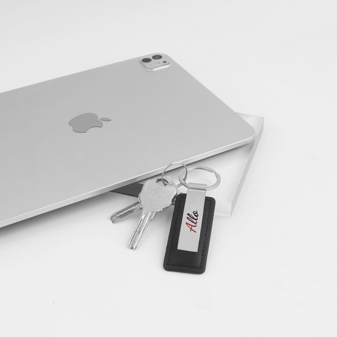 A PU leather metal keyring featuring a sleek design, alongside keys and a tablet on a white background.