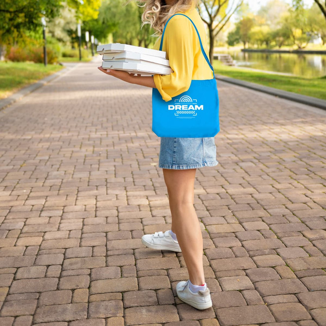 A bright blue canvas tote bag with a long strap, held by a person delivering four pizza boxes.