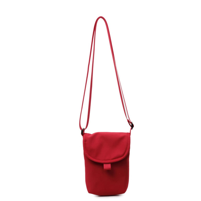 A small red canvas shoulder bag with a flap and adjustable strap. It has a simple, minimalist design.