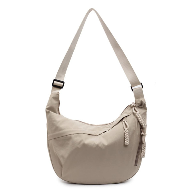 A beige crossbody bag with a woven zipper pull and an adjustable strap. It has a brand logo visible on the side.