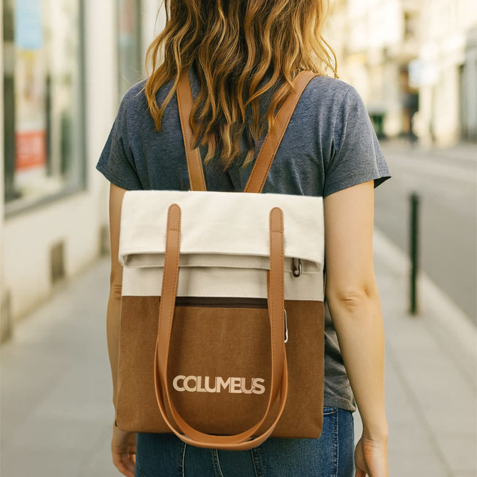 A woman walks down the street carrying a convertible canvas backpack in cream and brown with shoulder straps.