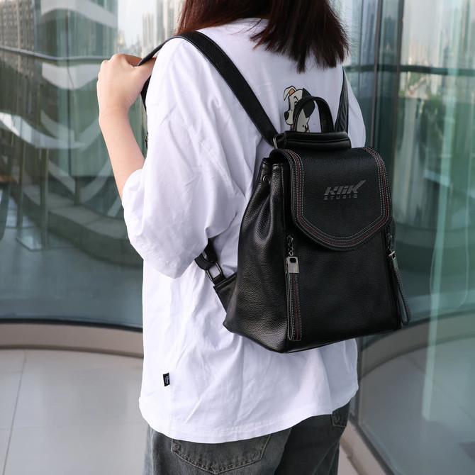 A black convertible leather backpack is worn on a person's back, featuring a stylish design and adjustable straps.