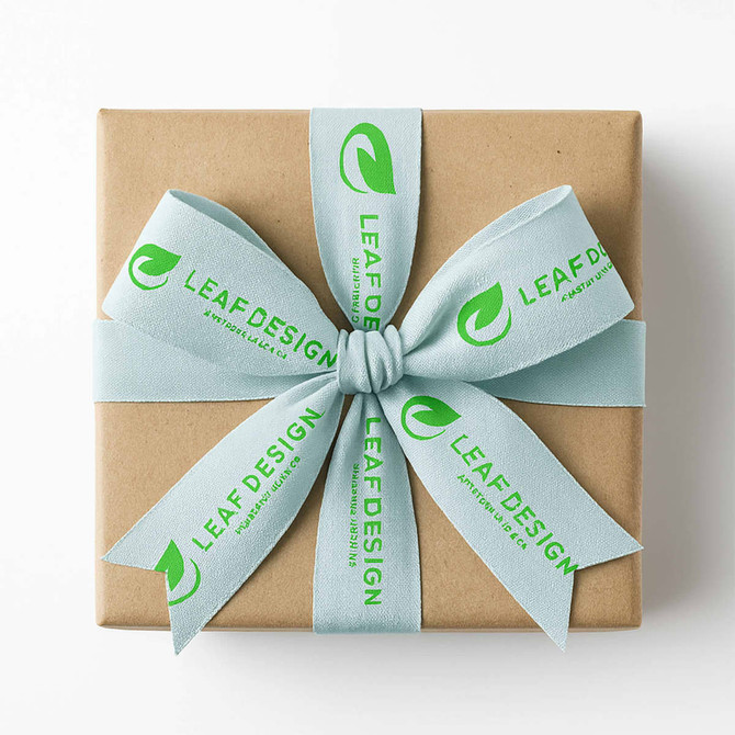 A gift box wrapped in brown paper, featuring a light blue satin ribbon with a logo and text printed on it.