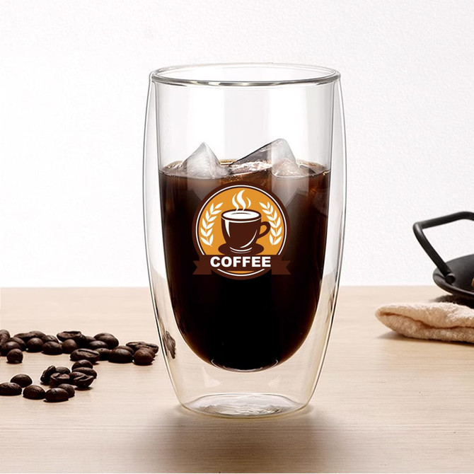 A glass drink bottle with double walls, containing iced coffee and surrounded by coffee beans. It has a logo.