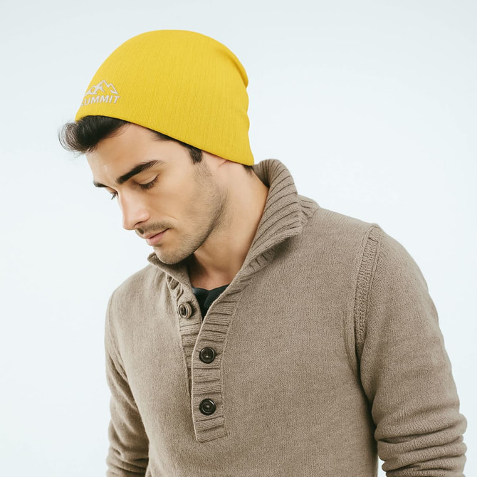 A yellow cable knit beanie worn by a man, with a casual brown sweater and branding on the beanie.