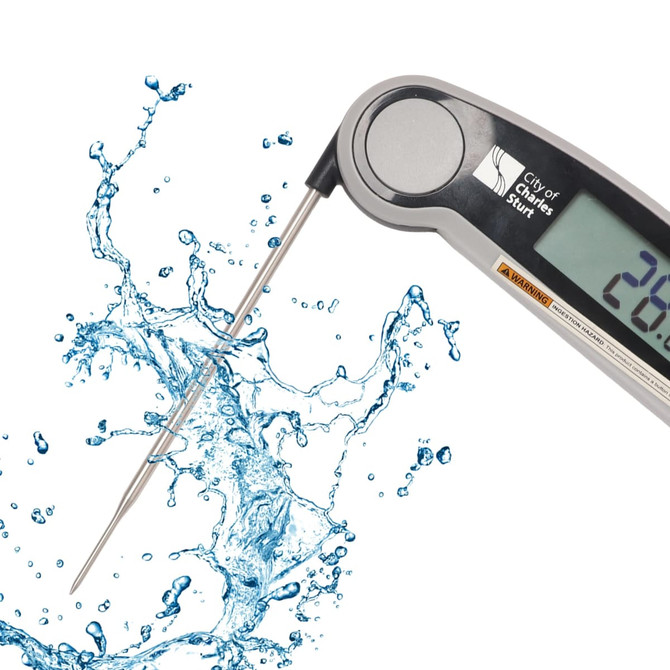 A digital instant read meat thermometer with a silver body and stainless steel probe, surrounded by splashes of water.