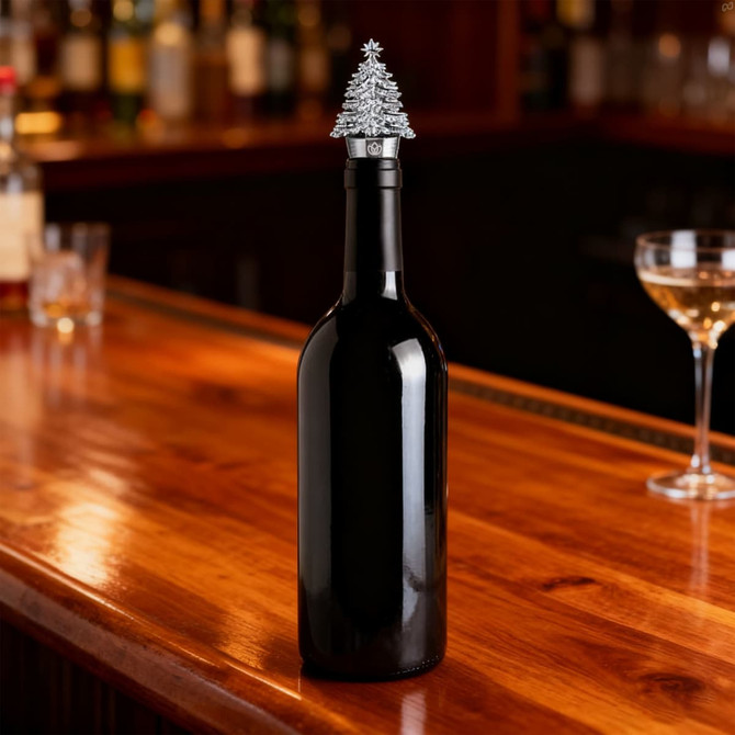 A drink bottle with a silver Christmas tree-shaped wine stopper on a wooden bar top.
