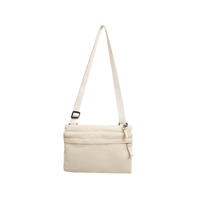 A lightweight crossbody bag in cream, featuring a zippered compartment and an adjustable strap.