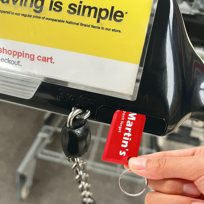 A red custom shape trolley coin keyring attached to a shopping trolley, with a logo visible.