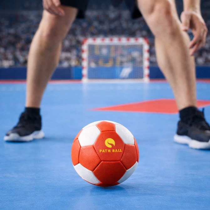 A red and white machine-stitched microfiber PU handball with a logo, positioned on a blue court.