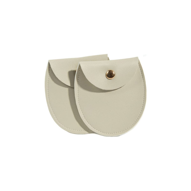 A pair of oval-shaped PU leather jewelry pouches in a light beige colour, featuring a snap button closure.