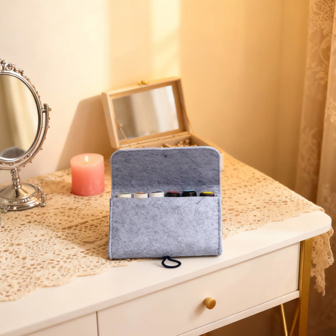 A grey felt essential oil bag opened on a table, displaying various essential oil bottles inside.