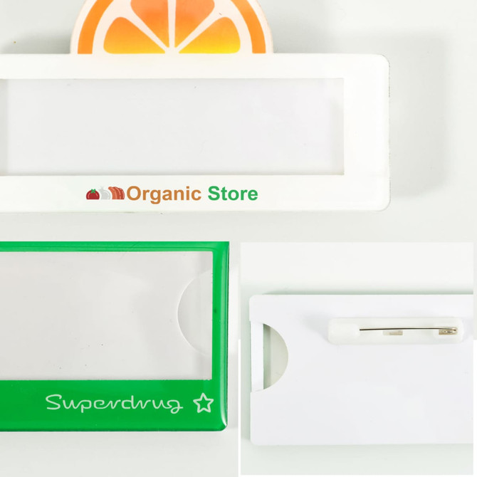 A custom reusable acrylic name badge in white and green, featuring a logo and a pin attachment.