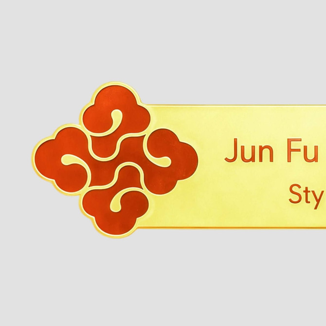 A custom metal name badge featuring a decorative red design and a gold background.