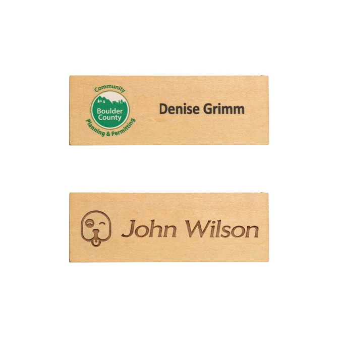 A wooden name badge in light brown with two engraved names and a logo, featuring a simple design.