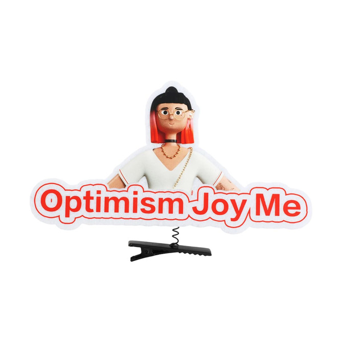 A custom felt hair clip featuring a character with red hair and the phrase "Optimism Joy Me" in bold text.